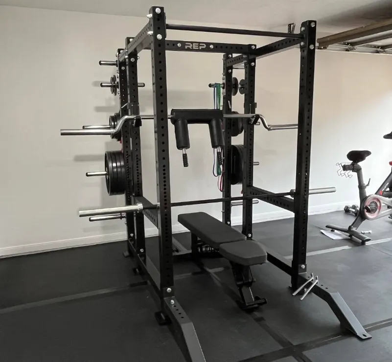 A complete home gym setup — squat rack, bench, barbell and plates arranged in a residential space.