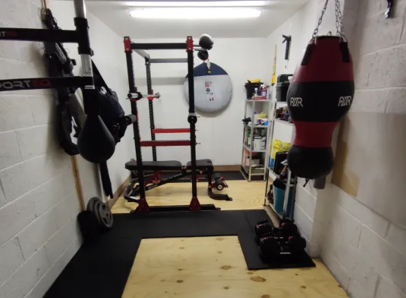 Matthew Morrison's red-and-black home gym — power rack, heavy bag, stacked plates.