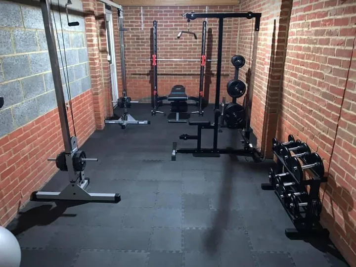 Shane Coady-Barrett's home gym in Cork, Ireland — squat rack, cable crossovers, adjustable bench.