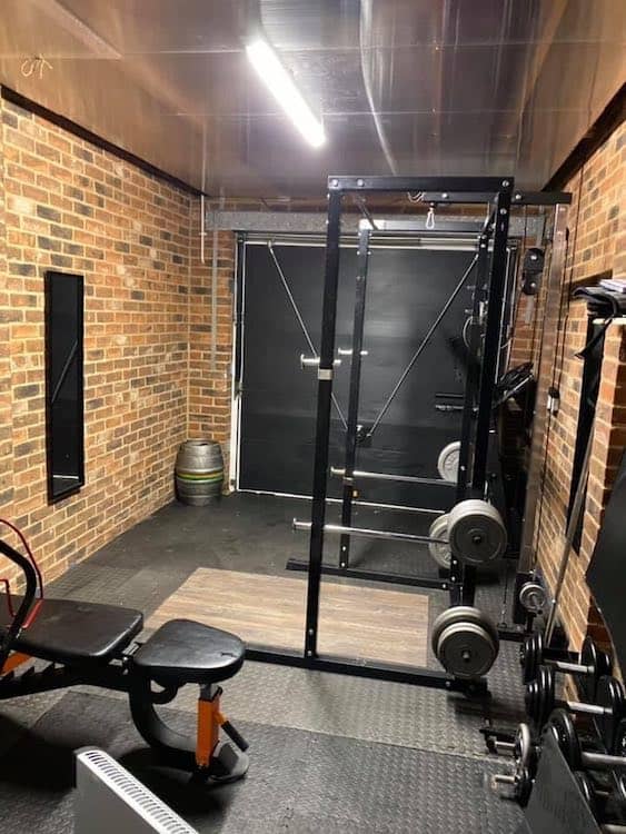 Garage gym with dumbbells, power rack, weight bench, plates and a barbell